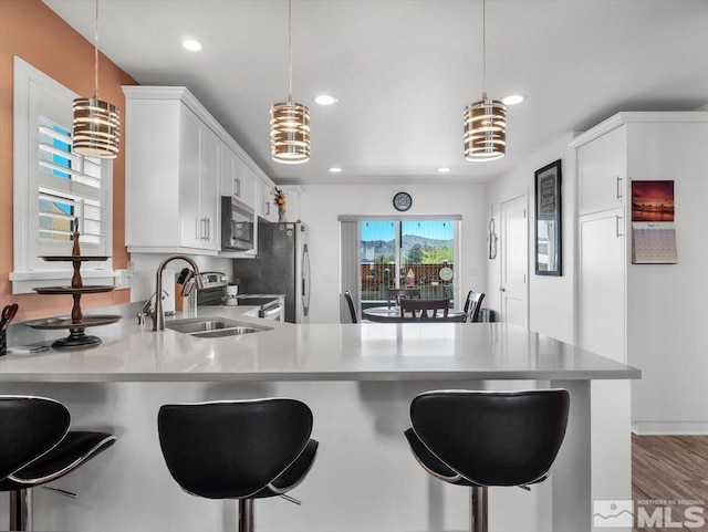 kitchen featuring white cabinets, sink, hanging light fixtures, and stainless steel appliances