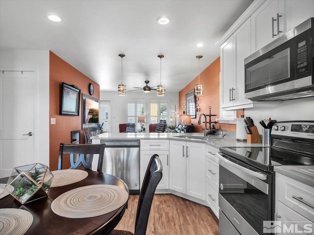 kitchen with pendant lighting, white cabinets, ceiling fan, appliances with stainless steel finishes, and kitchen peninsula