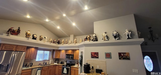 kitchen with light stone counters, sink, lofted ceiling, and stainless steel appliances