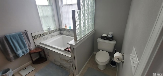 bathroom with tile patterned flooring, a relaxing tiled tub, and toilet