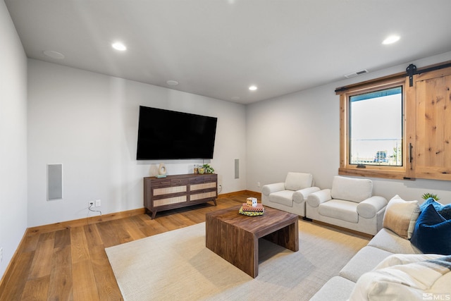 living room featuring a barn door and light hardwood / wood-style floors