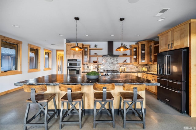 kitchen featuring wall chimney exhaust hood, a kitchen island, a breakfast bar, and high quality fridge