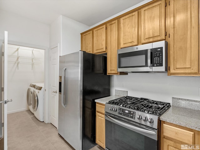 kitchen featuring light tile patterned flooring, washing machine and dryer, and stainless steel appliances