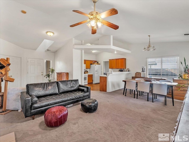 living room featuring ceiling fan with notable chandelier, light carpet, and vaulted ceiling