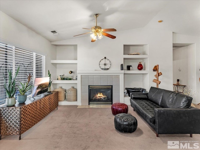 carpeted living room featuring a fireplace, vaulted ceiling, built in features, and ceiling fan