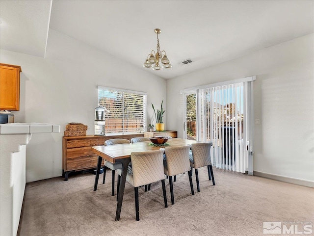 carpeted dining room featuring plenty of natural light, a chandelier, and vaulted ceiling