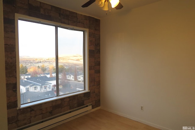 empty room with hardwood / wood-style floors, ceiling fan, a baseboard heating unit, and a healthy amount of sunlight