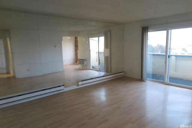 unfurnished room with a textured ceiling, wood-type flooring, and baseboard heating