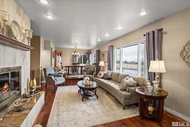 living room with a notable chandelier, dark hardwood / wood-style flooring, and a tile fireplace