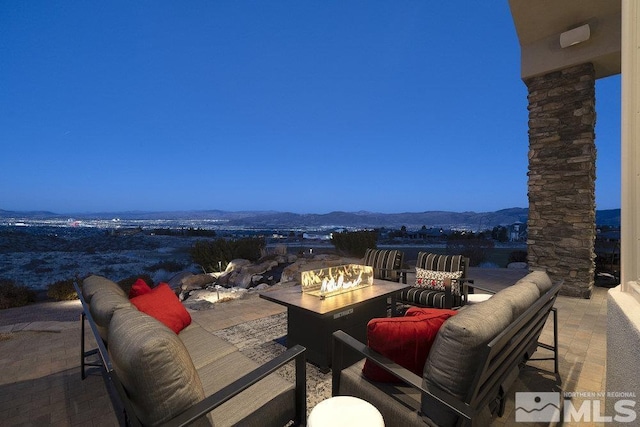 view of patio with a mountain view and an outdoor living space with a fire pit