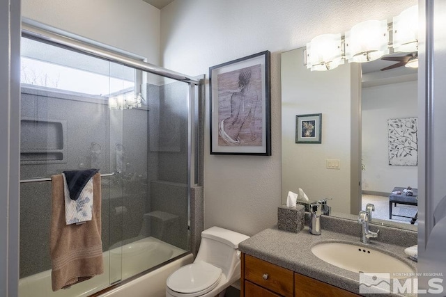 full bathroom with vanity, ceiling fan, toilet, and enclosed tub / shower combo