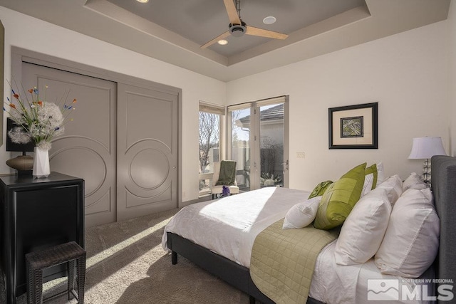 bedroom with carpet flooring, ceiling fan, and a tray ceiling