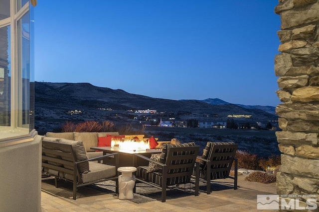 patio terrace at dusk featuring a mountain view and an outdoor living space with a fire pit