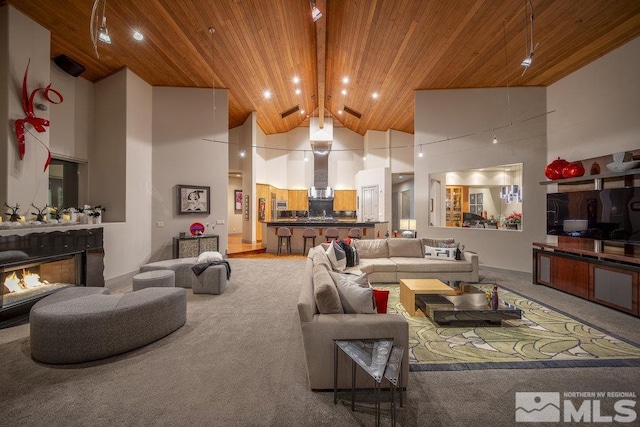 carpeted living room featuring a fireplace, beamed ceiling, high vaulted ceiling, and wood ceiling