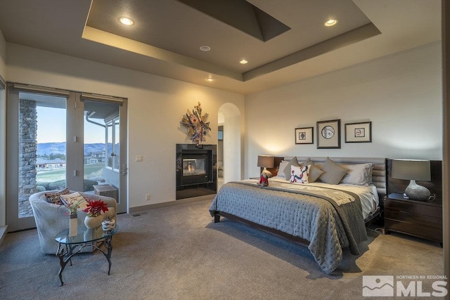 carpeted bedroom with a raised ceiling and access to outside