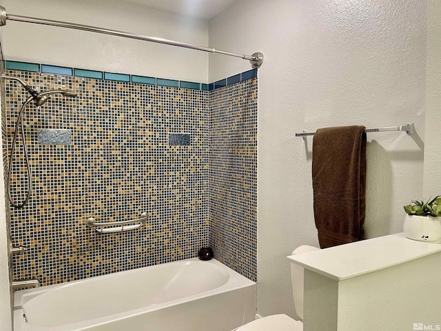 bathroom with toilet and tiled shower / bath