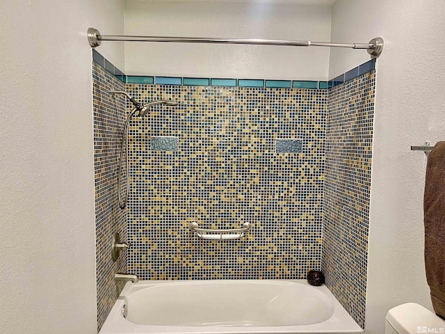 bathroom with toilet and tiled shower / bath