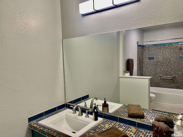 full bathroom featuring sink, tiled shower / bath combo, and toilet