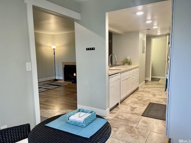 kitchen with white cabinets, sink, white dishwasher, and light tile patterned flooring