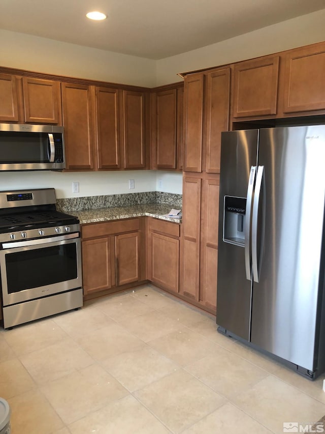 kitchen with dark stone countertops, light tile patterned floors, and appliances with stainless steel finishes