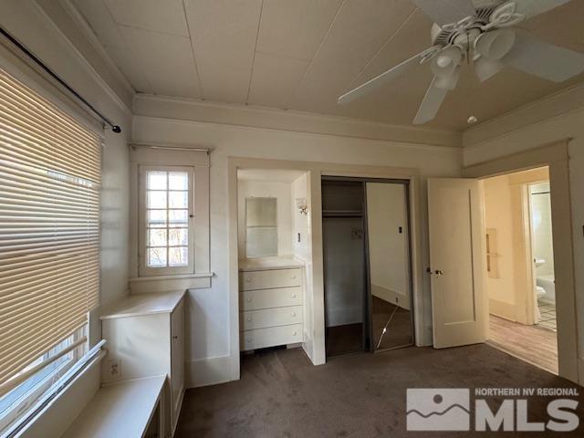 unfurnished bedroom featuring ceiling fan, a closet, and dark colored carpet