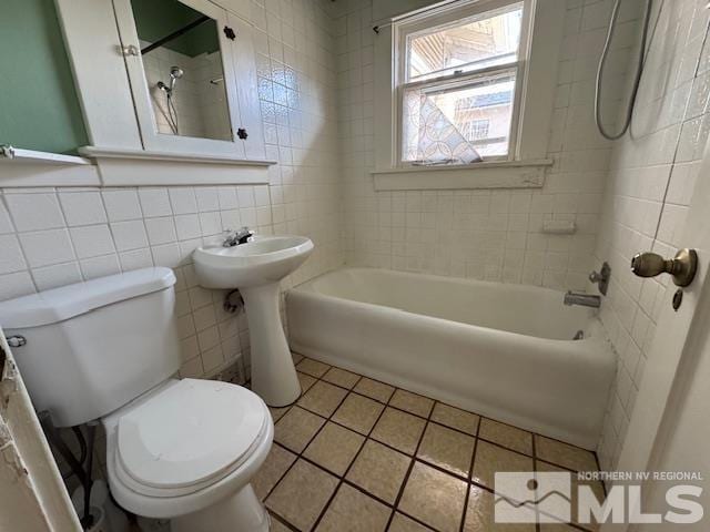 bathroom featuring tile patterned flooring, tiled shower / bath combo, toilet, and tile walls