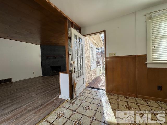 entrance foyer featuring a brick fireplace and wooden walls