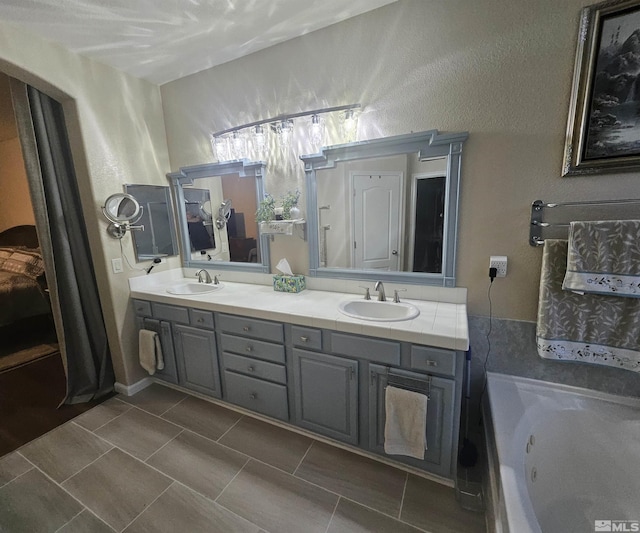 bathroom featuring tile patterned flooring, vanity, and a relaxing tiled tub