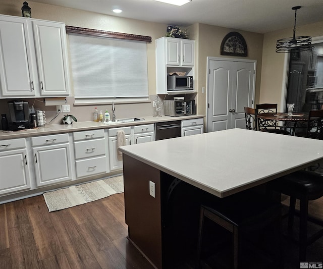 kitchen featuring white cabinetry, stainless steel appliances, a kitchen breakfast bar, dark hardwood / wood-style floors, and decorative light fixtures