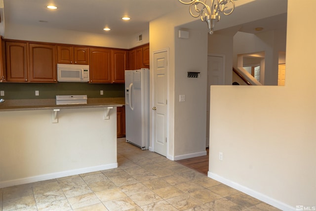 kitchen with an inviting chandelier, kitchen peninsula, decorative light fixtures, white appliances, and a breakfast bar