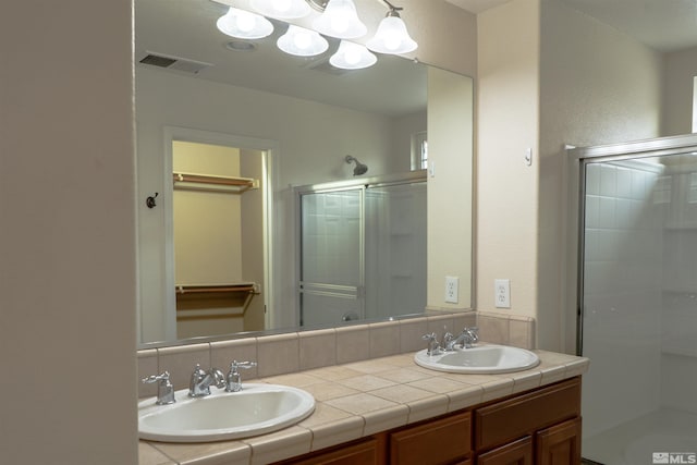 bathroom featuring a shower with door and vanity