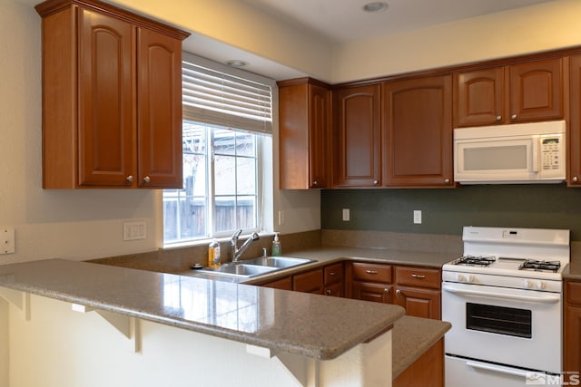 kitchen with light stone countertops, sink, kitchen peninsula, white appliances, and a kitchen bar