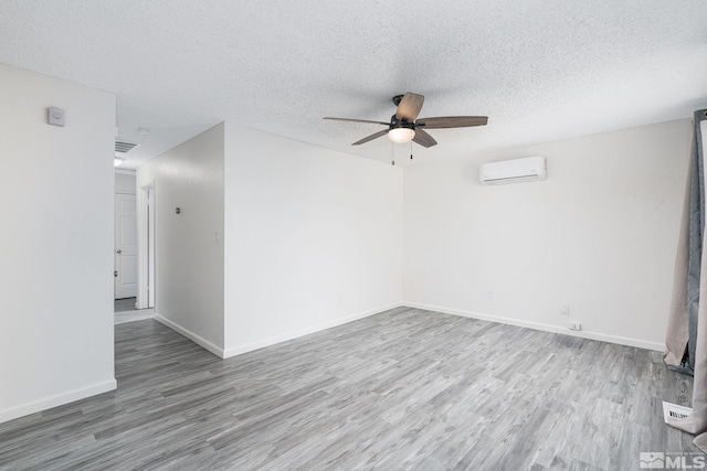 spare room featuring a textured ceiling, ceiling fan, hardwood / wood-style floors, and a wall mounted air conditioner