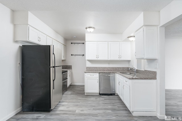 kitchen featuring sink, dark stone counters, a textured ceiling, white cabinets, and appliances with stainless steel finishes