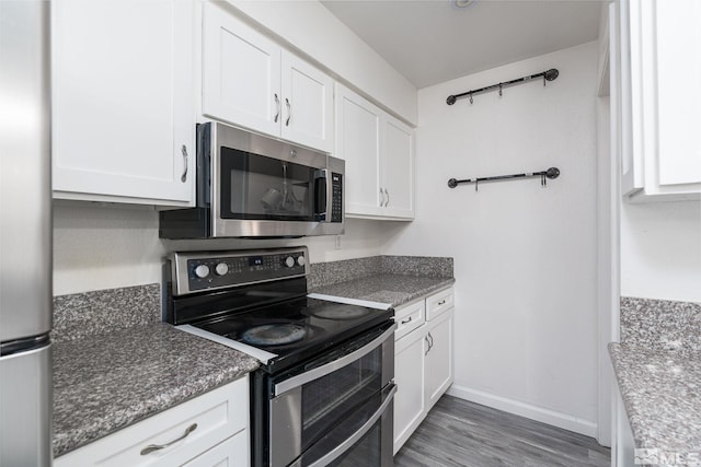 kitchen featuring white cabinets, appliances with stainless steel finishes, dark wood-type flooring, and dark stone countertops