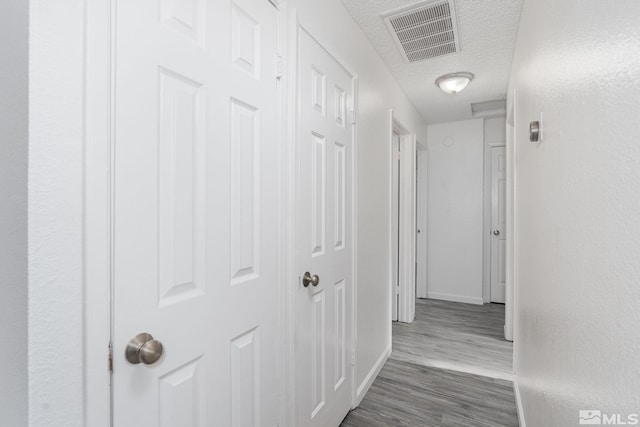 hallway with a textured ceiling and dark wood-type flooring