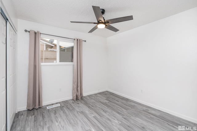 empty room featuring ceiling fan, light hardwood / wood-style flooring, and a textured ceiling