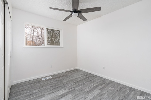 spare room with hardwood / wood-style flooring, ceiling fan, and a textured ceiling