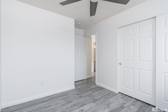 unfurnished bedroom with light wood-type flooring, a textured ceiling, a closet, and ceiling fan