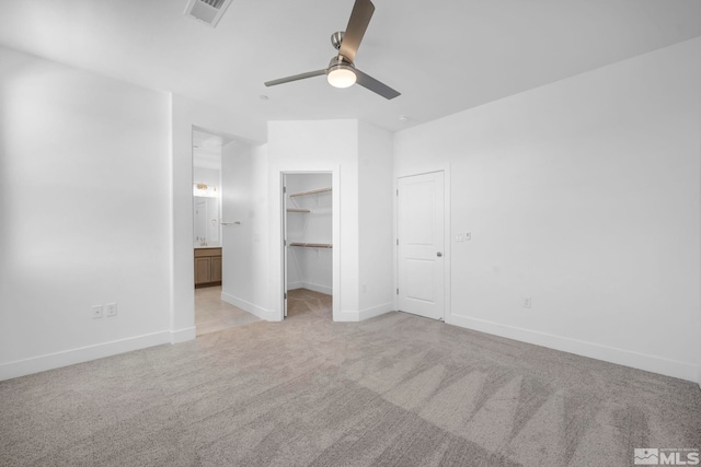 unfurnished bedroom with ensuite bath, ceiling fan, a spacious closet, light colored carpet, and a closet