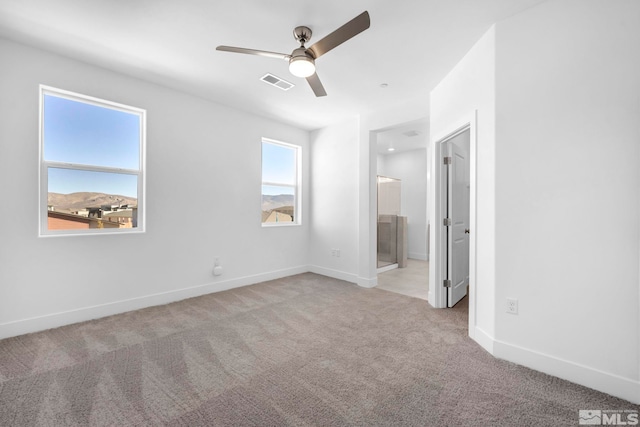 unfurnished bedroom featuring ensuite bath, light colored carpet, and ceiling fan