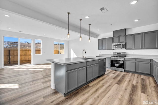 kitchen with appliances with stainless steel finishes, decorative light fixtures, sink, and gray cabinetry