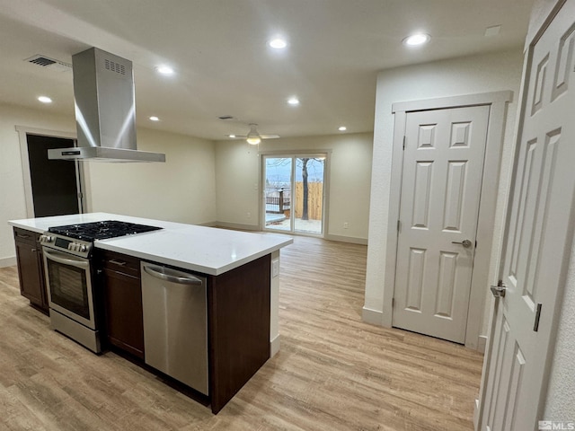 kitchen with ceiling fan, light hardwood / wood-style flooring, island exhaust hood, a kitchen island, and appliances with stainless steel finishes