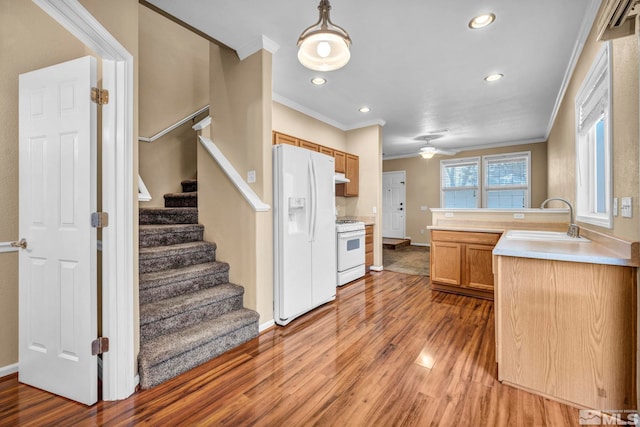 kitchen with white appliances, crown molding, sink, pendant lighting, and light hardwood / wood-style flooring