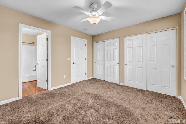 unfurnished bedroom with ensuite bath, ceiling fan, carpet, and two closets