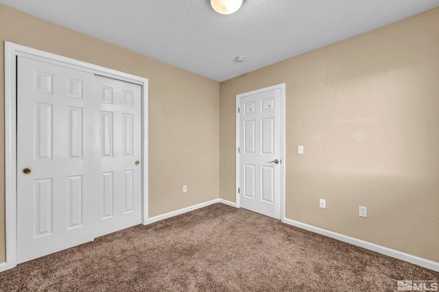 unfurnished bedroom with carpet floors, a textured ceiling, and a closet