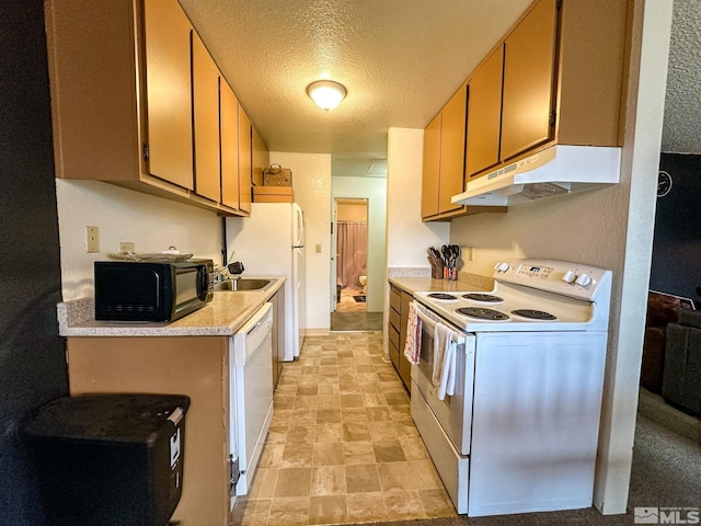 kitchen featuring sink, white appliances, and a textured ceiling