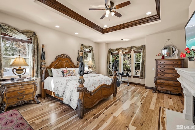 bedroom featuring ceiling fan with notable chandelier, light hardwood / wood-style floors, and multiple windows