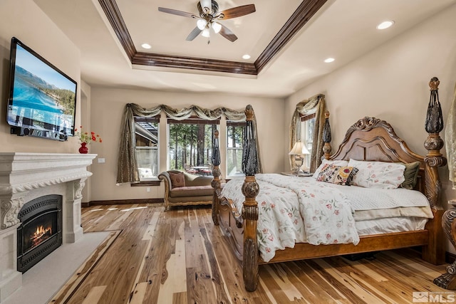 bedroom with wood-type flooring, a tray ceiling, ceiling fan, and crown molding