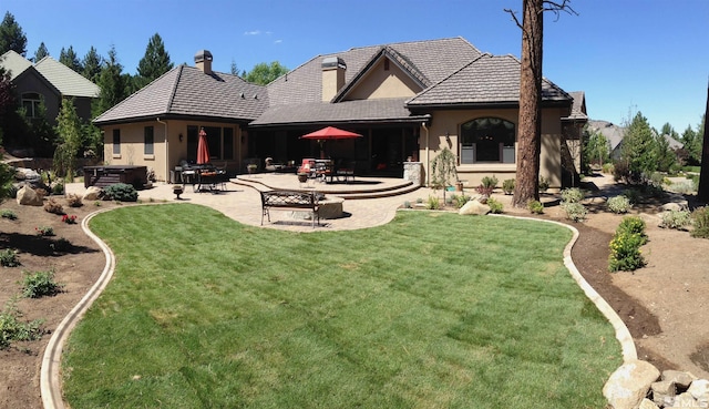 back of house with a lawn, a patio, and a hot tub